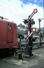 Signale und Sicherheitstechnik Der Lokf�hrer der 141 253-5 sieht sichernd aus dem Zug, w�hrend sich der Zug am freien Ausfahrsignal in Neustadt an der Weinstrasse im Juni 1994 in Bewegung setzt. Aus Sichtgr�nden sind/waren die Formsignale im Bahnsteigbereich verk�rzt und auch die Signalfl�gel waren verk�rzt. Aus Sicherheitsgr�nden ist um das Signal ein Schutzgel�nder erstellt.